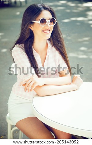 Young smiling pretty woman sitting alone at restaurant, having fun alone and whiting for her friends. Vintage colors.