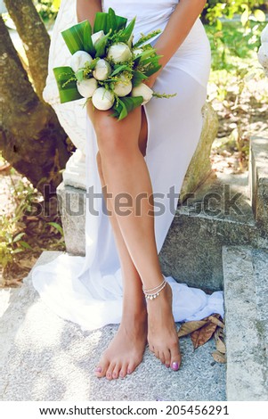 Fashion image of woman legs, bride sitting and posing with exotic lotus flowers, celebrate wedding in Thailand.
