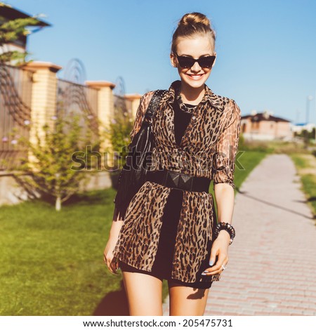 Young pretty stylish woman walking alone at beautiful summer day in short black dress and leopard printed shirt, wearing cat eye sunglasses, smiling an having fun.