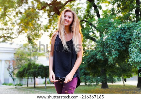 Young pretty girl posing at city park at nice sunny day, have stylish ombre blonde hairs.