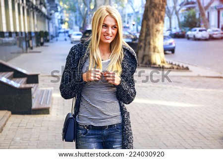 Pretty smiling tender sensual blonde posing at the street at cozy relaxed trendy fall autumn outfit, walking alone at city center.