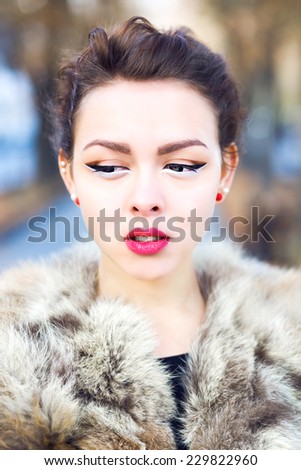 Close up fashion portrait of sensual asian woman with bright make up and perfect skin , wearing fur jacket, posing on the street at autumn fall time. Pastel soft colors.