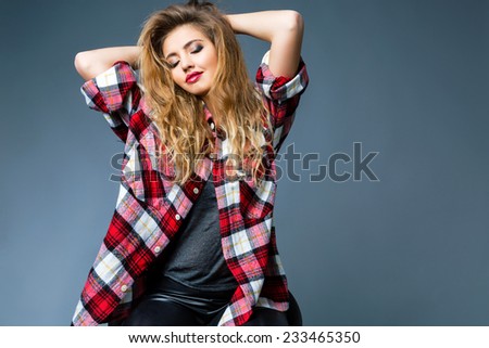Fashion studio portrait of beautiful woman with amazing hairs and beautiful face, wearing bright smoky rock make up, and big relaxed grunge plaid shirt. Posing alone, grey background.
