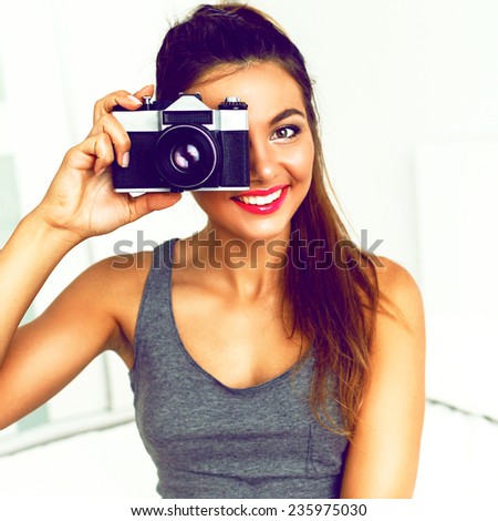 Close up lifestyle portrait of young pretty photographer girl making shot on her vintage camera, white background, bright Instagram colors.