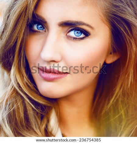 Close up fashion portrait of blonde sexy girl with magnetic blue eyes, stylish hairstyle and bright makeup.