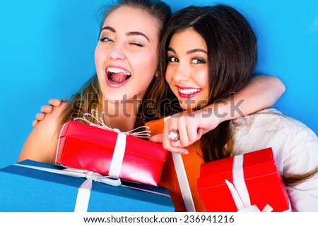 Close up bright portrait of two funny pretty friends women hugs having fun and holding holiday presents, exiting emotions ready for celebration.