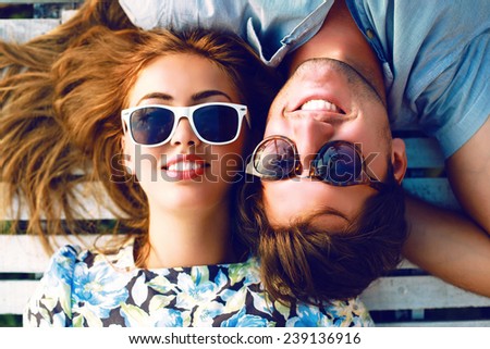 Fashion lifestyle portrait of young perfect couple lay and relaxed on their vacation, wearing sunglasses and vintage clothes, bright sunny summer colors.