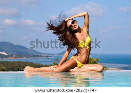Outdoor fashion portal of glamour lady enjoying her vacation ingot tropical island.Vitality and delightfully woman wearing yellow bikini,sunglasses wish elegant,long hair.Amazing views of mountains