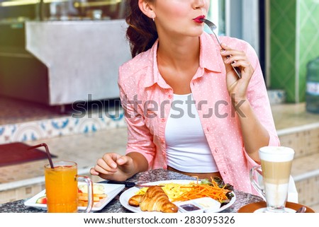 Close up image of young woman eating classic breakfast a tasty omelet, fresh croissants, coffee and fresh juice oranges. This energy boost for the whole day.