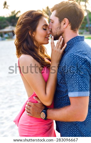 Summer stylish fashion sensual portrait of a happy, sexy couple in love.Gorgeous, young, beautiful lovers, on vacation in a tropical country. Kissing and hugs.