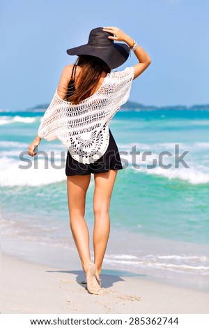 Summer fashion portrait of amazing fit sexy woman posing in the front of blue ocean on tropical hot exotic island, wearing romper and vintage hat, bright colors,joy, vacation.