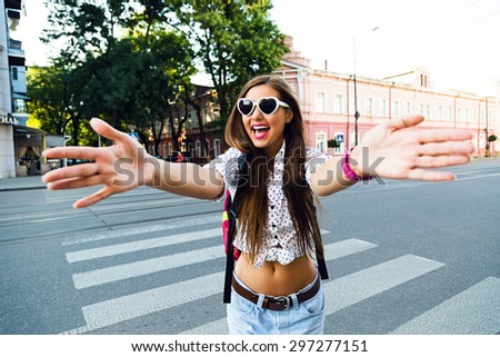 Young hipster woman going crazy and having fun in city center of Europe, walking and traveling alone, joy, emotions, casual stylish clothes and backpack, put her hands to the camera.