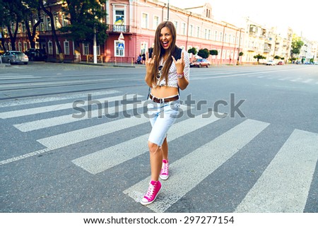 Young hipster woman going crazy and having fun in city center of Europe, walking and traveling alone, joy, emotions, casual stylish clothes and backpack, sunny bright colors.