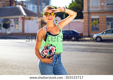 Young hipster girl having fun on the street, wearing summer stylish outfit , crop top, swag hat and mirrored sunglasses.