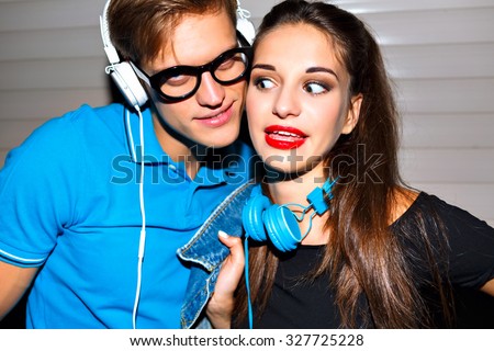 Young cheerful couple going crazy together, emotional funny faces, urban party, listening music at stylish big  headphones, hipster couple in love.