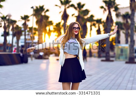Young hipster woman walking at evening time, posing at sunset at California city,  bright colors. warm autumn time, hipster trendy stylish outfit make up and sunglasses.