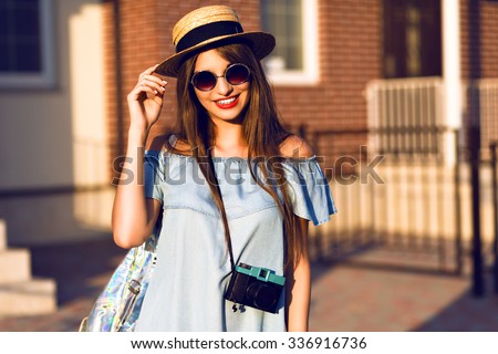 Young pretty hipster cheerful girl posing on the street at sunny day, having fun alone, stylish vintage clothes hat and sunglasses, travel concept , young photographer with vintage camera.