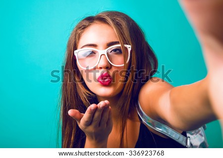 Young sexy woman with bright make up ant amazing brunette hairs making selfie, sending air kiss, studio hipster portrait.