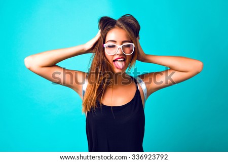 Young pretty sexy girl going crazy alone, blue mint background. showing long tongue, close her eyes, cheeky mood, clear hipster glasses.