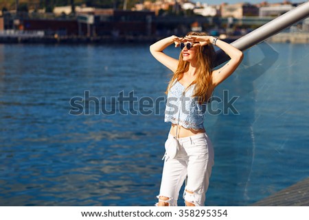 Romantic sea view portrait of sensual blonde woman,trendy summer outfit, pastel colors, travel alone, vacation, white denim, sunglasses.