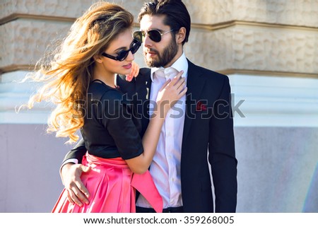 Young elegant sexy couple hugs on the street, wearing suit and glamour evening dress, enjoy their honeymoon vacation in Europe, luxury style, love, stylish lovers.