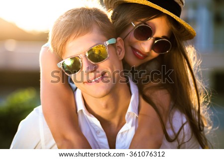 Close up romantic beauty portrait of happy hipster couple in love hugs and having fun, evening sunlight, stylish sunglasses, hat, emotions, joy, youth, sunny colors, hugs and kisses, vintage style.