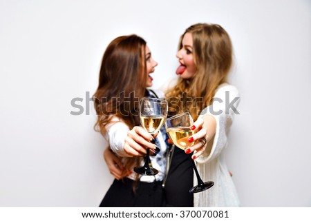 Fashion party portrait of elegant funny sister girls having fun laughing and gossip, ready for celebration drinking champagne, black and white glamour party,bright makeup , joy, emotions, cheers.