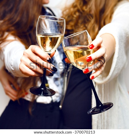 Close up image of woman hands with stylish manicure holding glasses with champagne , black and white style, party time. Cheers.
