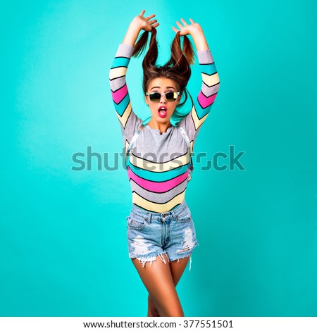 Fashion studio portrait of glamour sportive girl, smart casual outfit, cute emotions, stylish hipster clothes sunglasses and backpack, spring pastel colors. mini hipster denim shorts crazy emotions.