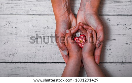 Baby\'s hand giving a heart to mother\'s hand. Love and care between kid and mom. Mother\'s day or woman\'s day concept.