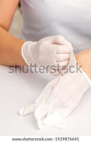 Close up of hands of nurse or female doctor puts on white rubber protective gloves over the table