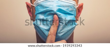 A doctor or nurse points to a medical mask on face with finger making a gesture to maintain silence. The need for and prevention of precautions for the coronavirus covid-19. High resulotion image.