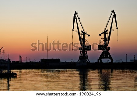 Cargo cranes in the port at sunset - silhouette