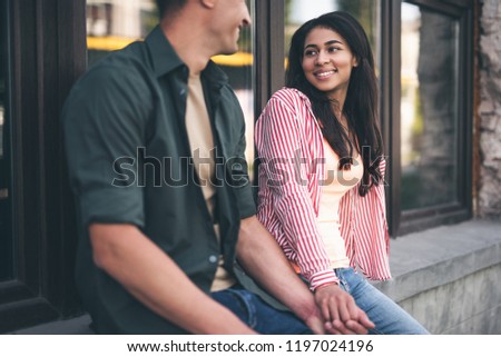 Young and romantic. Attractive long haired young woman looking at the handsome man while smiling and holding his hand
