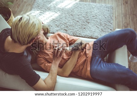Simple joy of loving. Top view portrait of young man with tattoo on arm laying head on boyfriend lap