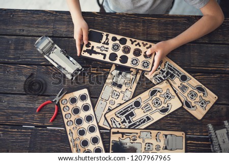 Horizontal photo of wooden constructor in the hands of a child sitting at the table