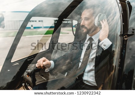 Serious elegant businessman looking calm while sitting in the helicopter cabin alone