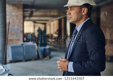 Side view photo of serious director of construction company locating in facility. Copy space on left side