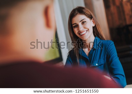 Concept of friendly atmosphere on meeting. Waist up selective focus on young cheerful woman sitting in cafe with man