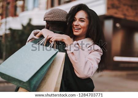 Close up portrait of happy woman embracing with beloved man on city background while going shopping together