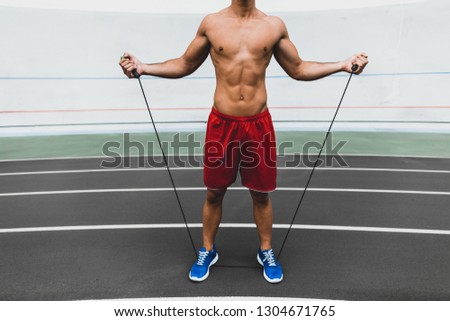 Young stripped to waist male athlete with attractive body jumping with sport equipment. He wearing shorts and modern trainers