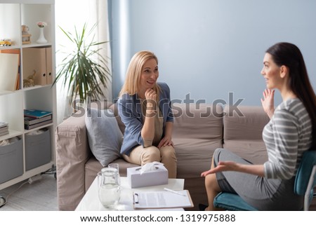 Doctor and client looking at each other while sitting on sofa in cabinet. Psychology help concept