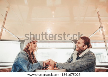 Visiting interesting coffee houses. Waist up side on portrait of happy man and woman holding hands while talking in cafe bus