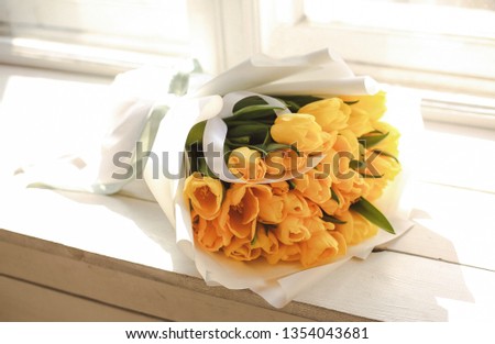 photo of beautiful bouquet of yellow tulips in paper packaging