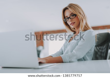 Calm woman looking confident while sitting at the workplace in modern office with her hands on the table