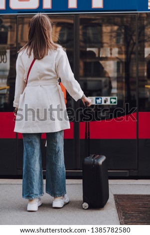 Full length back view portrait of lady in white trench coat standing on the street