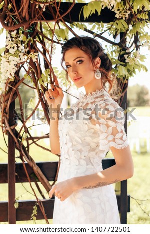 fashion outdoor photo of beautiful woman in elegant white dress posing in flowering spring garden