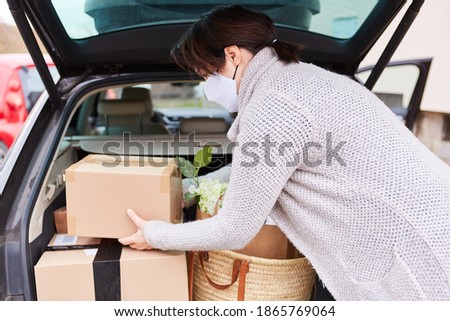 Woman with face mask loads full car trunk with packages and purchases
