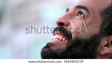 Hopeful man in 40s opening eyes to sky with FAITH, close-up face eye open