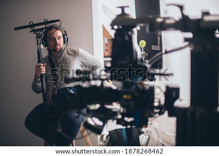 Sound engineer with a microphone on the set. A professional sound engineer at work on the filming of a movie, commercial or TV series. Filming process indoors, studio